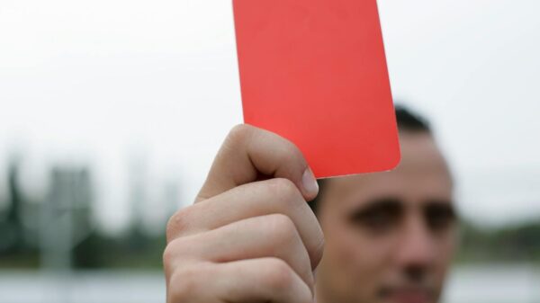 Close-up of a referee holding a red card, signaling a penalty in a soccer match.