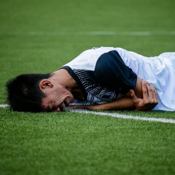 Soccer player lies on the field in pain during a game, indicating possible injury.