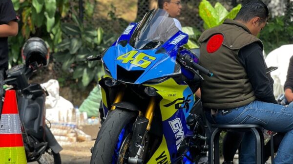 A group of people sitting around a blue and yellow motorcycle