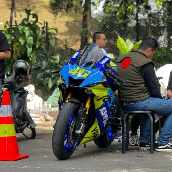 A group of people sitting around a blue and yellow motorcycle