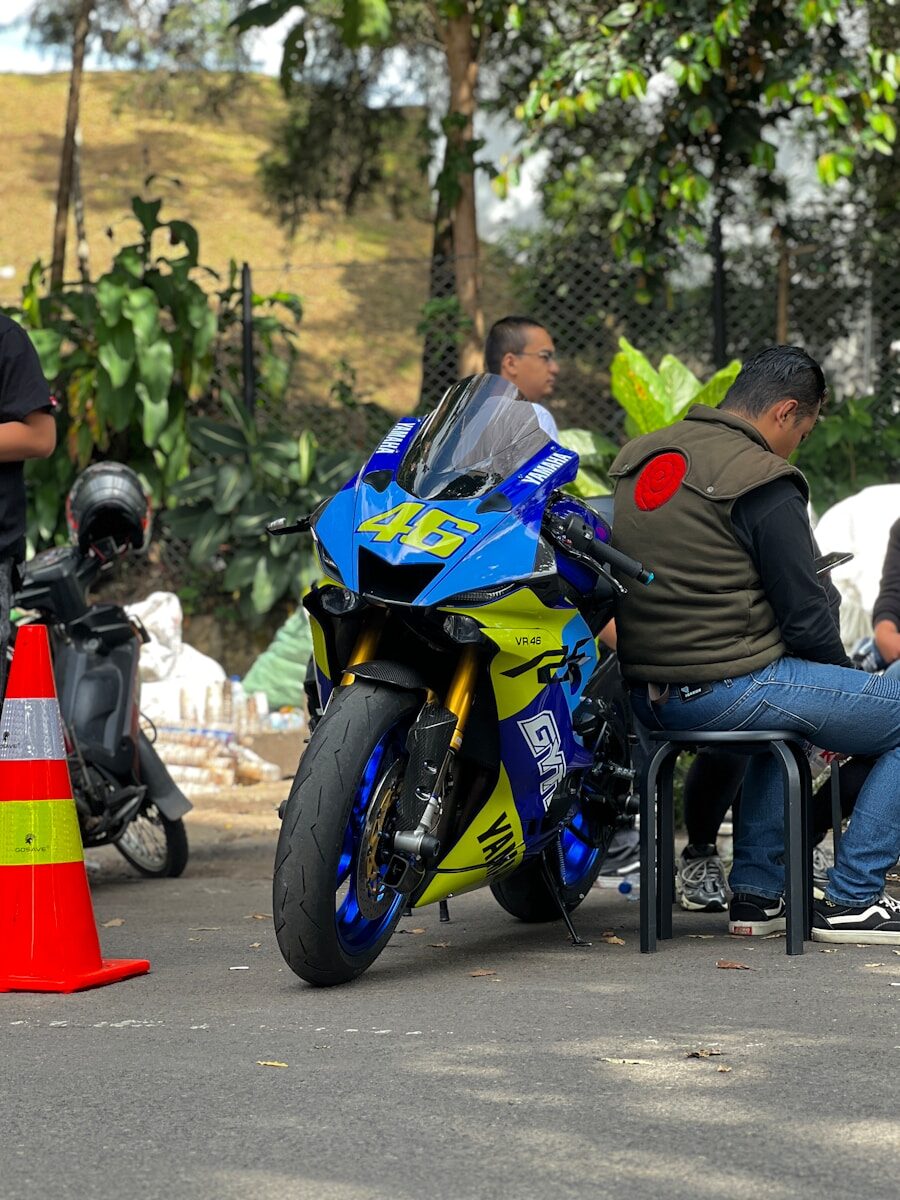 A group of people sitting around a blue and yellow motorcycle