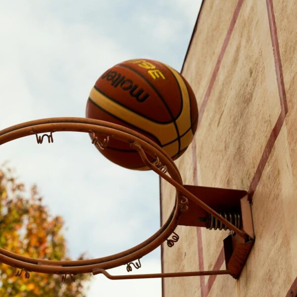 Basketball in motion as it goes through the hoop on an outdoor court.