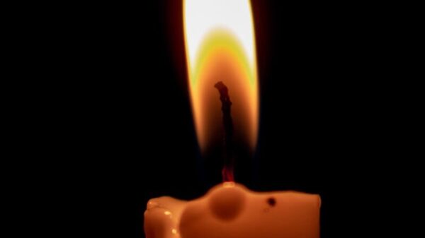 A burning candle casting a warm glow in the dark, highlighting serenity and calmness.