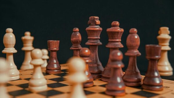 High-angle view of chess pieces on a wooden board, highlighting a strategic game.