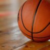 Close-up shot of a basketball on a wooden indoor court floor.