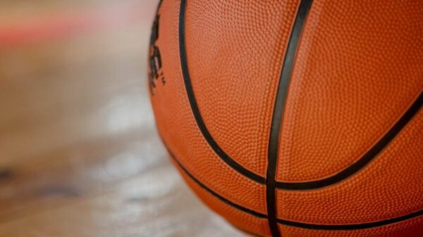 Close-up shot of a basketball on a wooden indoor court floor.