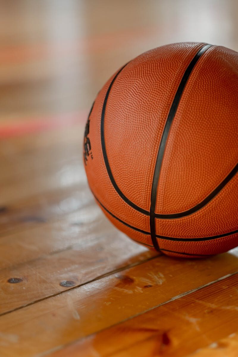 Close-up shot of a basketball on a wooden indoor court floor.