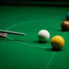 Focused shot of a snooker cue aiming at colored balls on a green table.