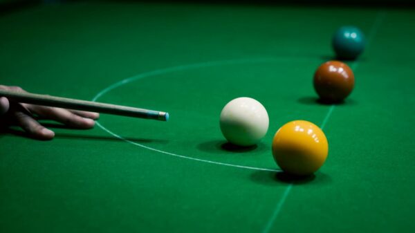 Focused shot of a snooker cue aiming at colored balls on a green table.