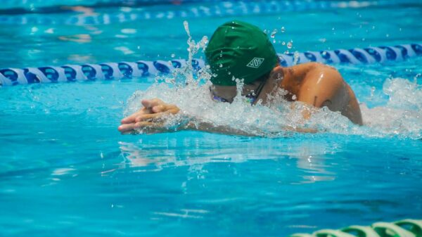 Focused swimmer in a pool during a race, featuring dynamic water splashes and vibrant turquoise water.