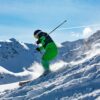 Skier in vibrant green outfit carving through snowy slopes in Vorarlberg, Austria.