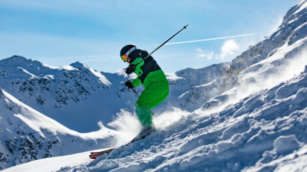 Skier in vibrant green outfit carving through snowy slopes in Vorarlberg, Austria.