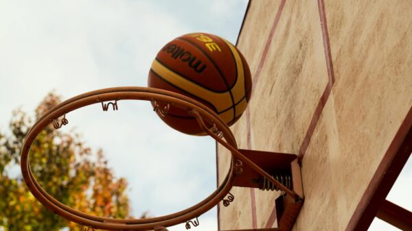Basketball in motion as it goes through the hoop on an outdoor court.