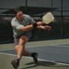 man in gray crew neck t-shirt and gray shorts sitting on basketball court