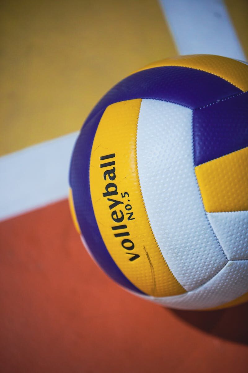 Colorful volleyball on an indoor court with visible lines, showcasing sports equipment.