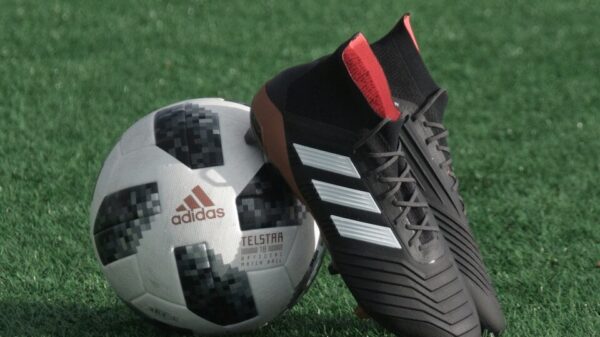 black adidas cleats lean on white and black adidas soccer ball on green grass