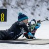 a person laying on a snow covered ground with a rifle