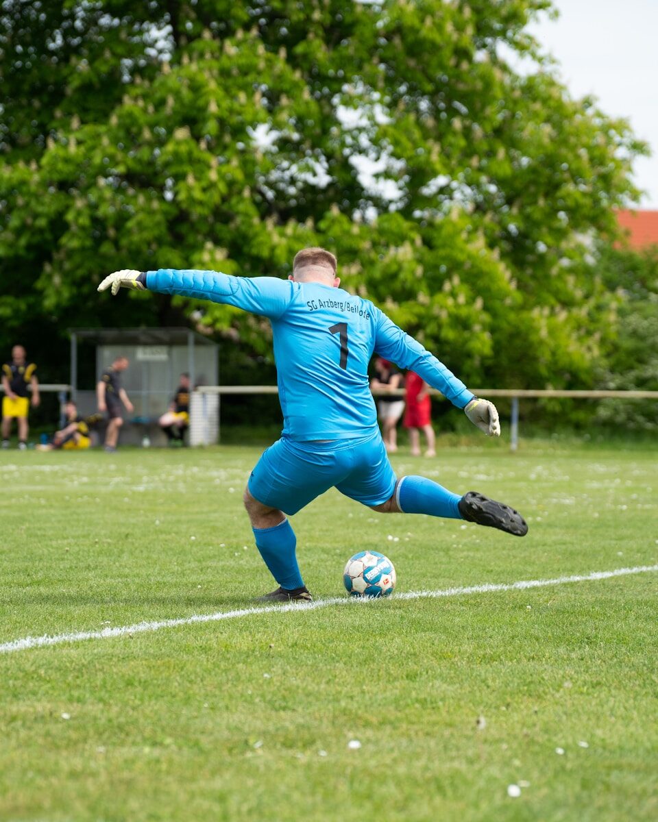 A soccer goalkeeper kicks the ball on the field.