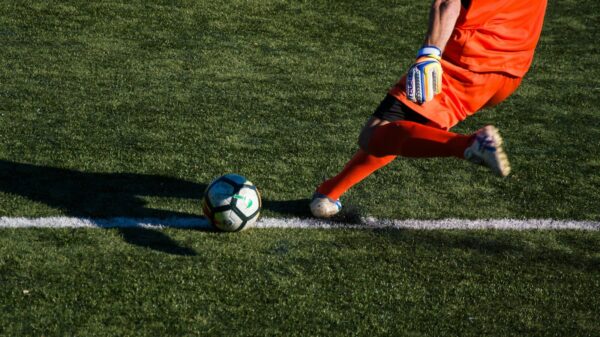 man kicking soccer ball on field