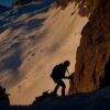 a man climbing up the side of a snow covered mountain