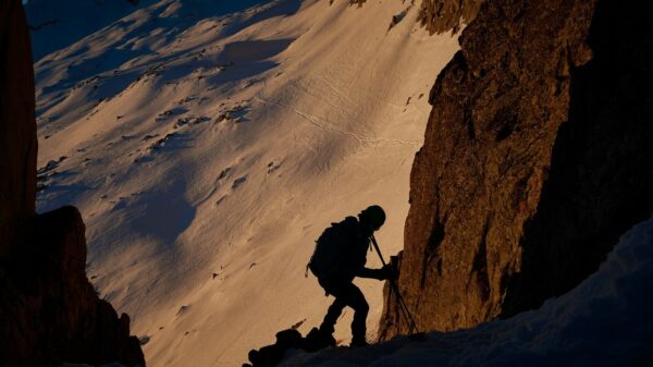 a man climbing up the side of a snow covered mountain