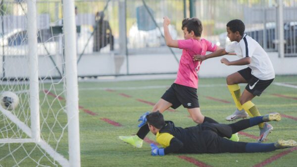 2 boys playing soccer on field during daytime