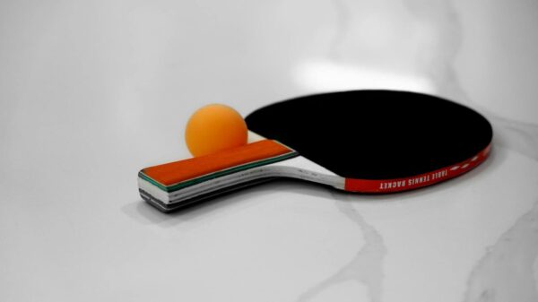Close-up of a table tennis racket and orange ball on a white background.