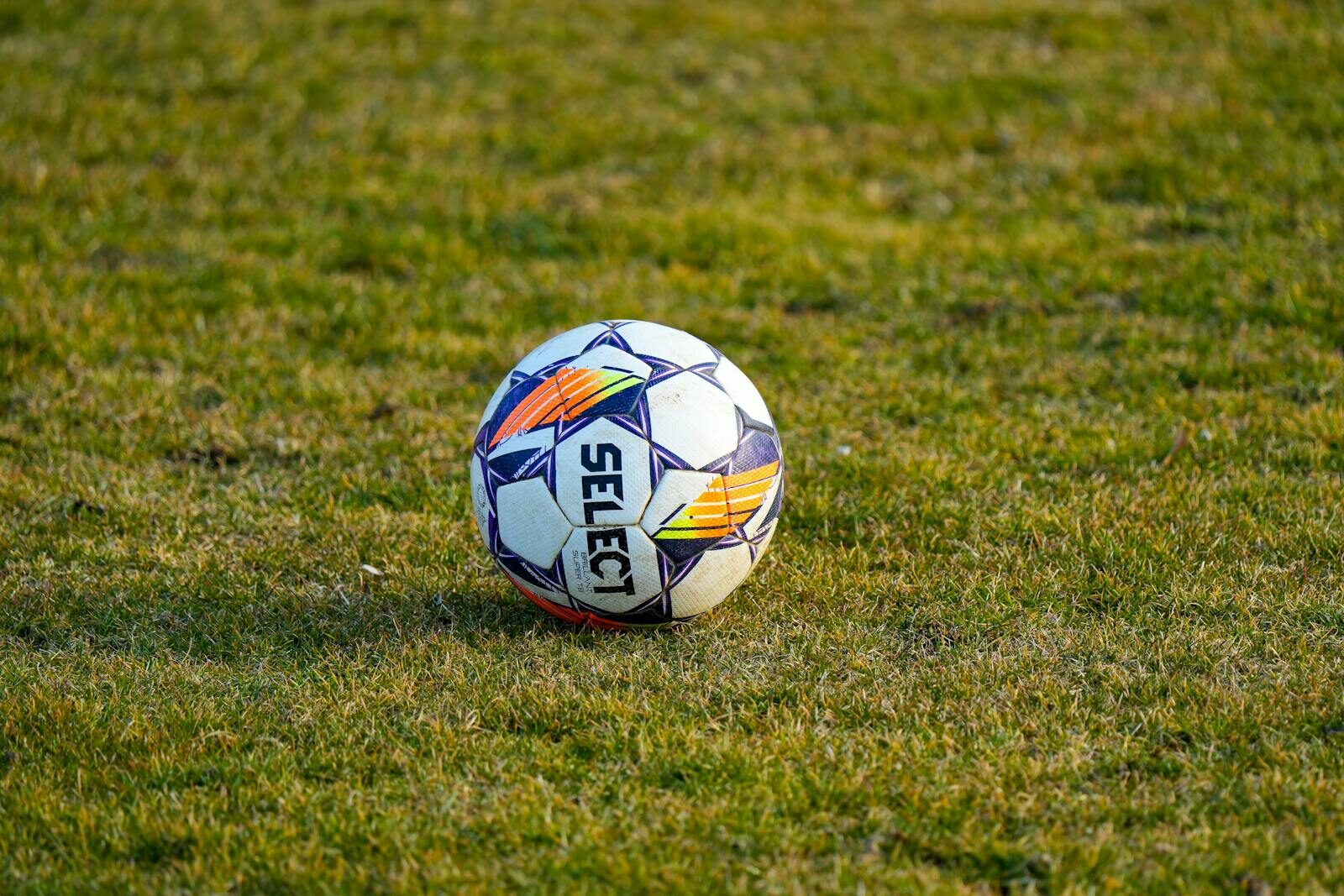 Close-up of a soccer ball on a grassy field under daylight. Perfect sports venue scene.