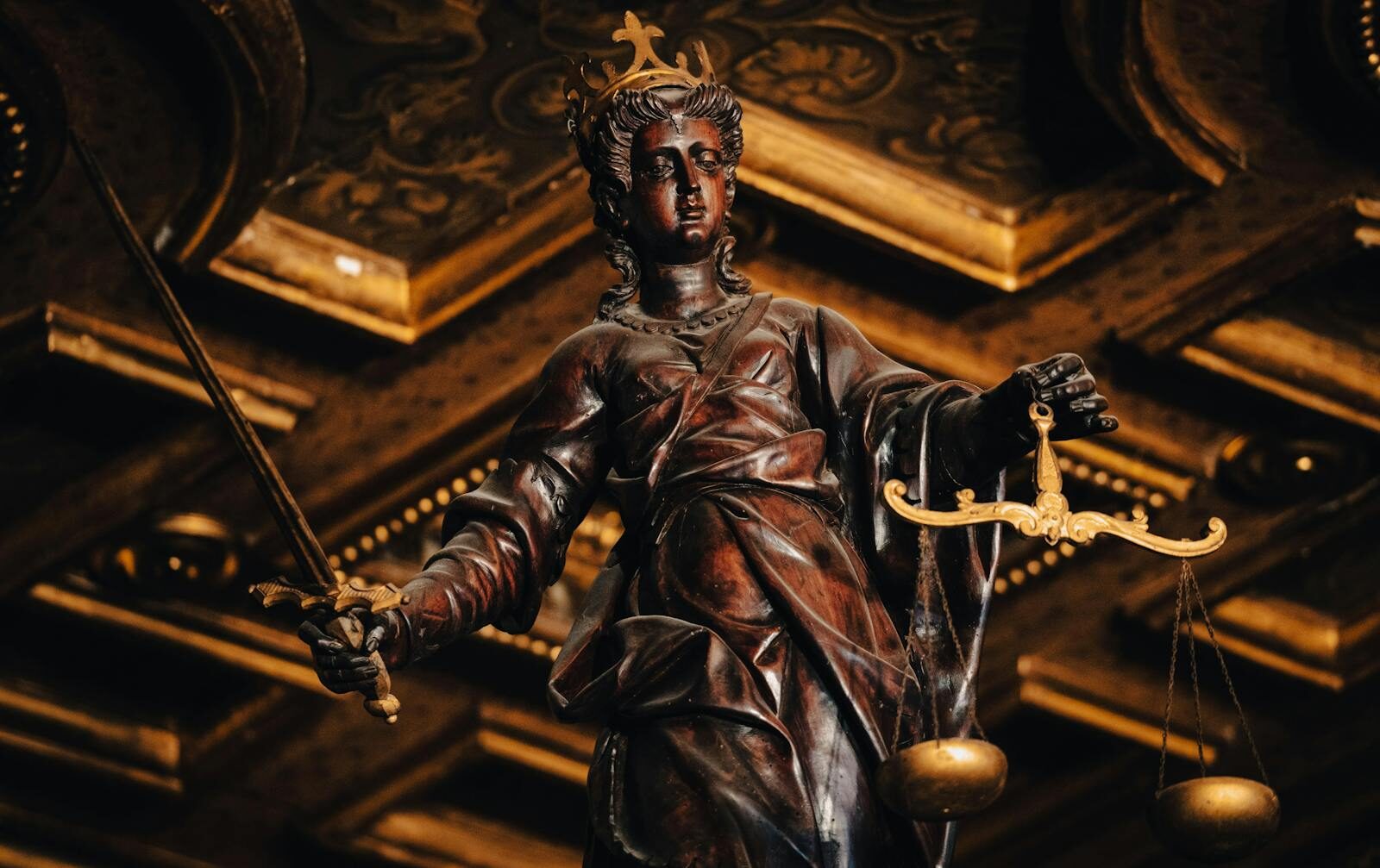 Detailed statue of Lady Justice holding scales and sword indoors with rich textures.