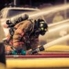 Firefighter in full gear handling water hose during emergency response training outdoors.