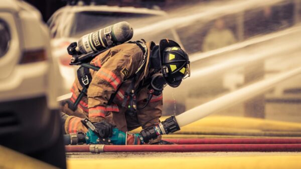 Firefighter in full gear handling water hose during emergency response training outdoors.
