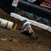 Motocross rider races down a steep dirt track.