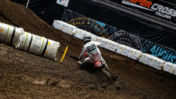 Motocross rider races down a steep dirt track.