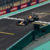 Formula 1 car speeding across the finish line on a racetrack, emitting sparks.