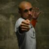 A man with a bald head pointing his finger at the camera