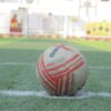 Close-up of a soccer ball on a green field with white lines, ready for play.