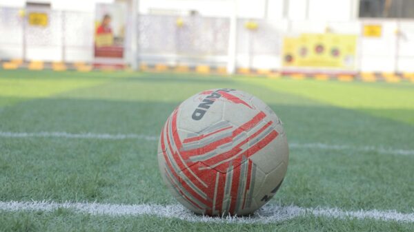 Close-up of a soccer ball on a green field with white lines, ready for play.