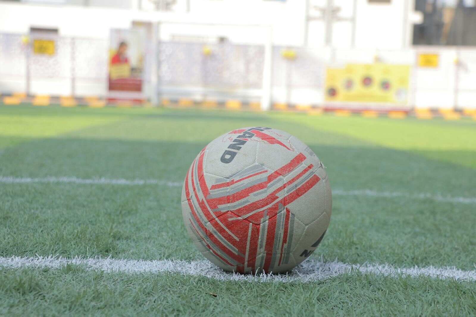 Close-up of a soccer ball on a green field with white lines, ready for play.