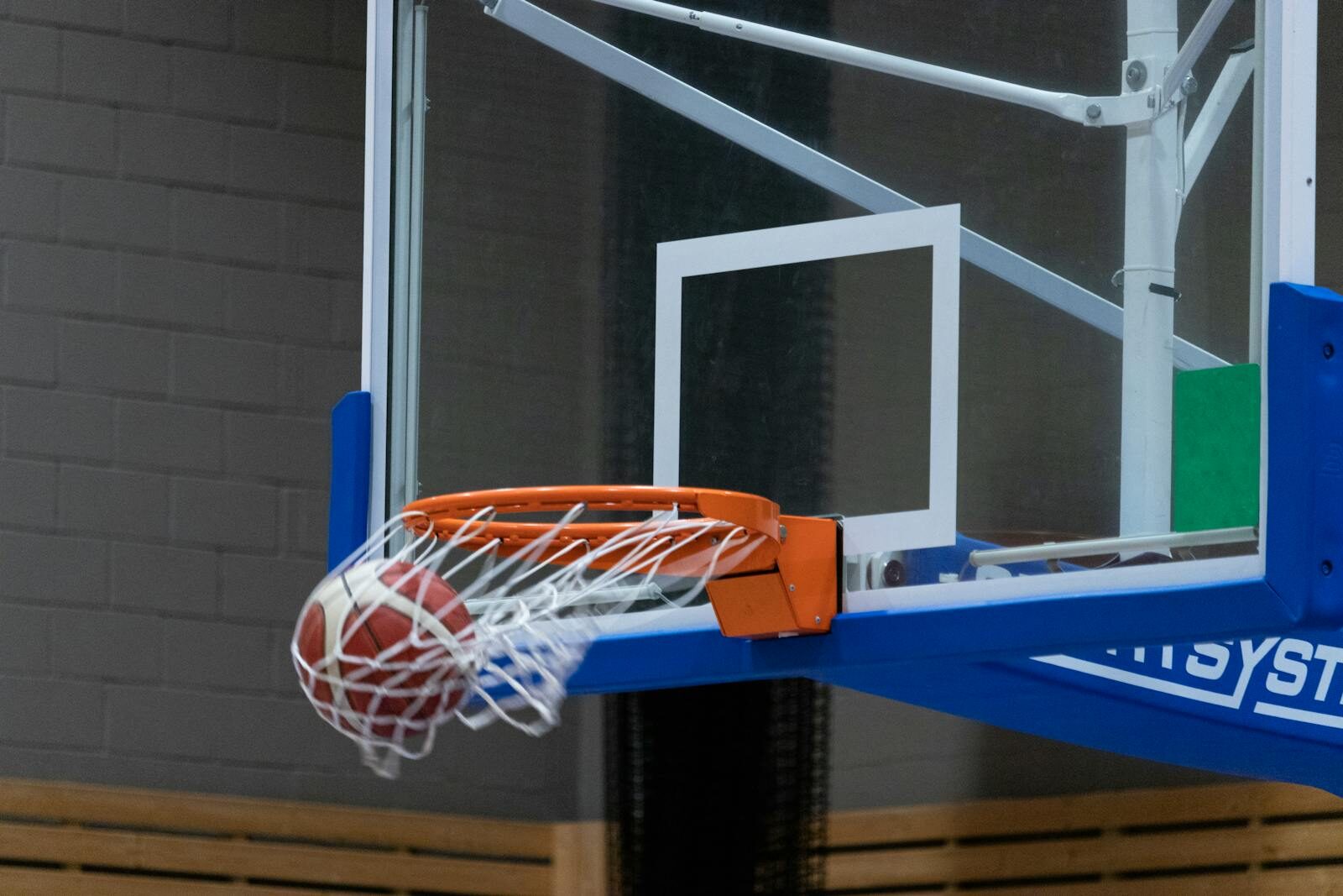 Close-up of a basketball scoring through the hoop in an indoor court setting.