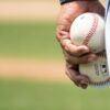 person holding two baseballs