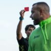 A man in a green hoodie holding up a red card
