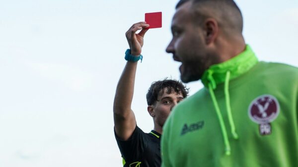 A man in a green hoodie holding up a red card