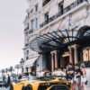 yellow sport car parked on street surrounded group of people