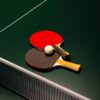 Table tennis paddles and ball on a green table. Ideal for sports themes.