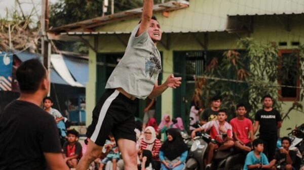 man in white crew neck t-shirt and black shorts holding yellow volleyball