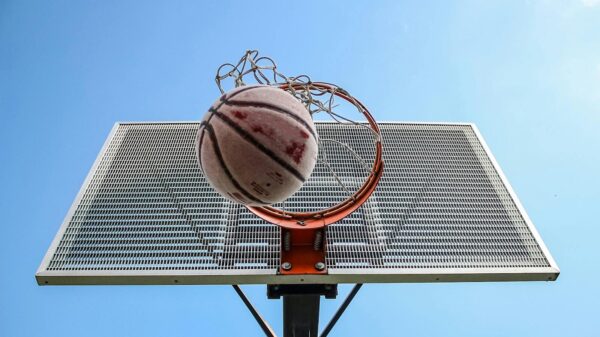 A low-angle shot of a basketball making its way through the hoop against a clear blue sky.
