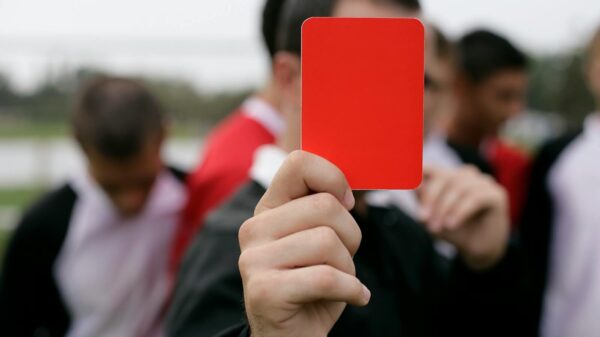 Referee showing a red card to players during an outdoor soccer game.