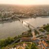 Stunning aerial view of a cityscape with a central river and a bridge at sunset.