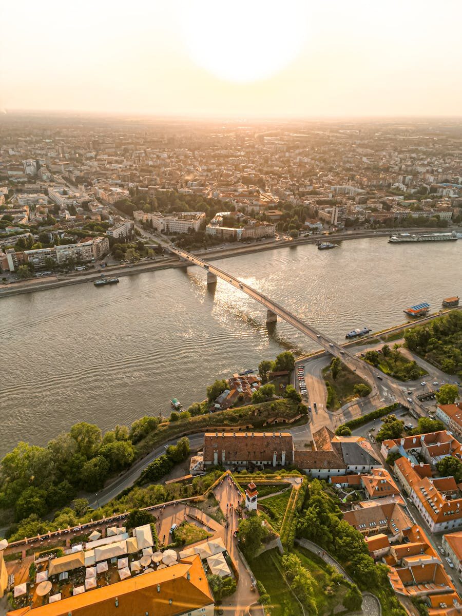Stunning aerial view of a cityscape with a central river and a bridge at sunset.