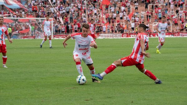 Players in action during a competitive soccer match with a vibrant crowd in the stadium.